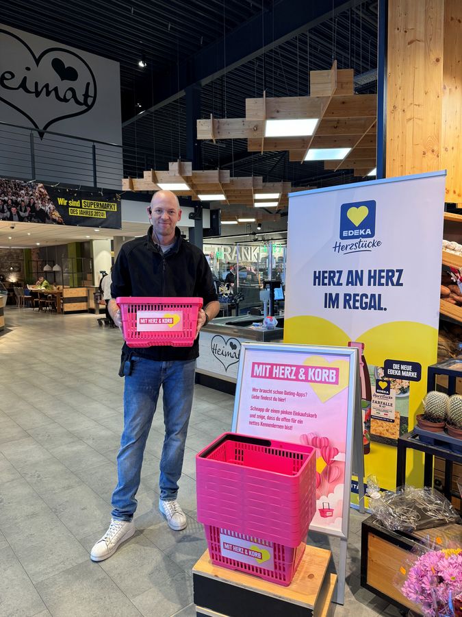 Peter Kirstein vom Elli-Markt Delbrück präsentiert die pinken Einkaufskörbe der Aktion „Mit Herz & Korb – Liebe geht durch den Einkaufskorb!“