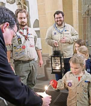 Paderborner Pfadfinder entzünden im Dom Kerzen an der Flamme des Friedenslichts.