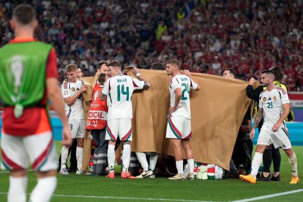 Die ungarischen Spieler halten einen Sichtschutz, während Stürmer Barnabas Varga behandelt wird. - Foto: Antonio Calanni/AP