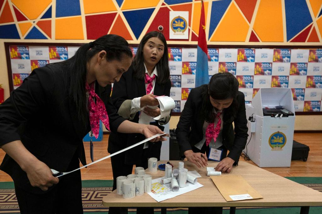 Wahlhelfer überprüfen die Ausdrucke der Ergebnisse von den Stimmauszählungsmaschinen nach Schließung der Wahllokale. - Foto: Ng Han Guan/AP/dpa