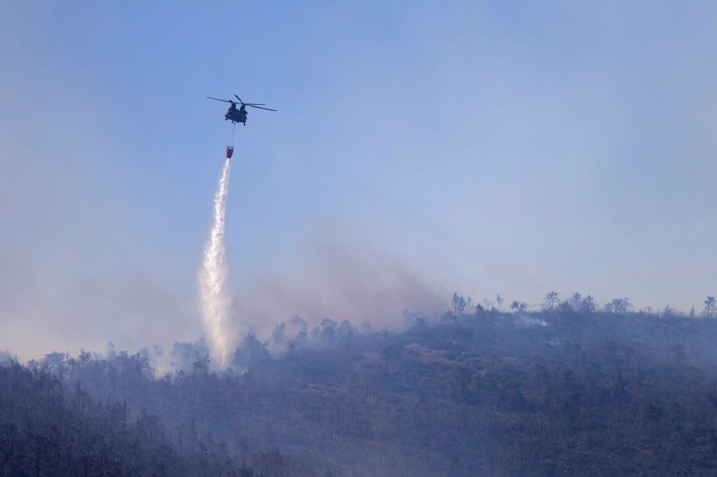Ein Hubschrauber wirft Wasser auf einen Waldbrand im Norden Athens ab. - Foto: Yorgos Karahalis/AP