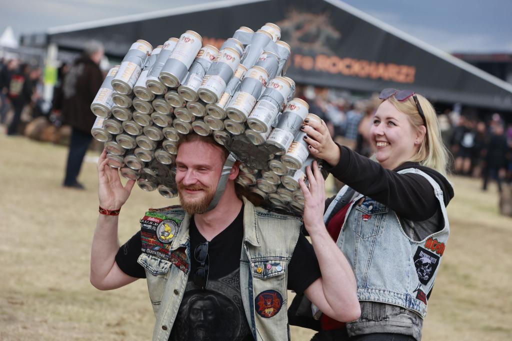 Gut behütet: Ein Besucher des Festivals Rockharz hat sich eine Kopfbedeckung aus Getränkedosen gebastelt und läuft über das Festivalgelände. - Foto: Matthias Bein/dpa