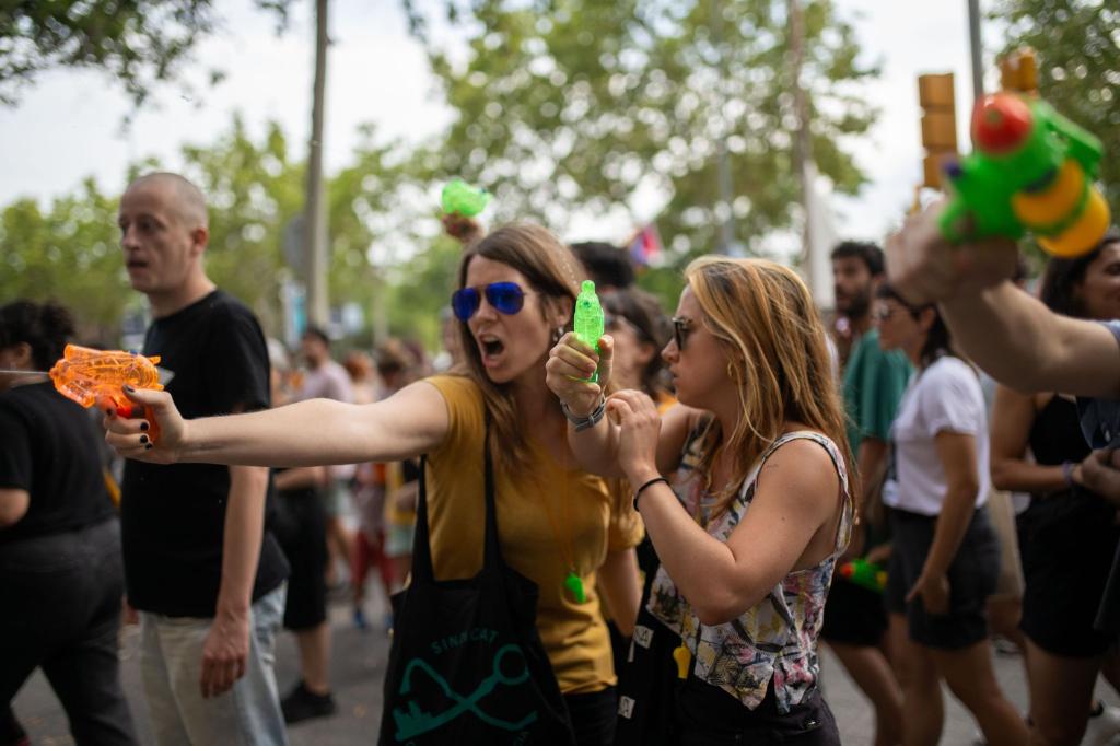 Demonstrantinnen verpassen Urlaubern eine unerbetene Abkühlung aus Wasserpistolen. - Foto: Lorena Sopêna/EUROPA PRESS/dpa