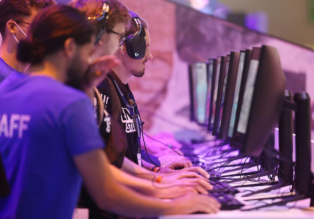 Messebesucher testen ein Computerspiel bei der Gamescom 2022. - Foto: Oliver Berg/dpa