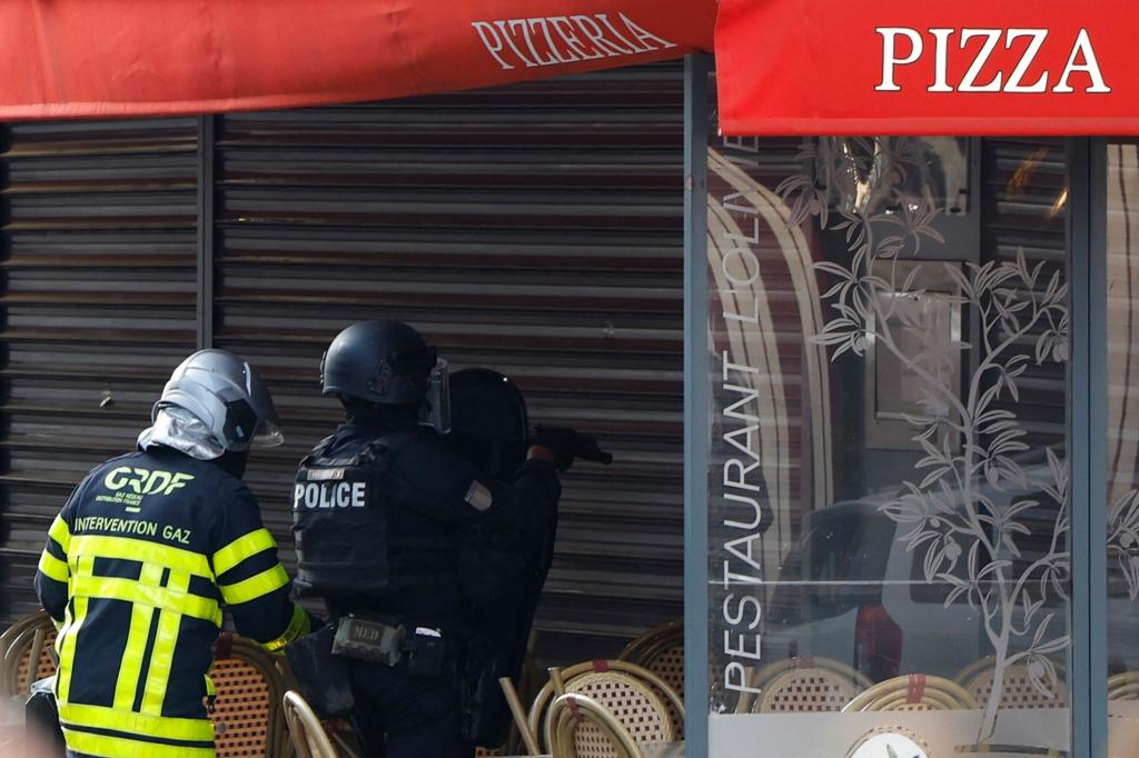 Polizisten stehen vor dem Restaurant in Issy-les-Moulineaux. - Foto: Ian Langsdon/AFP/dpa