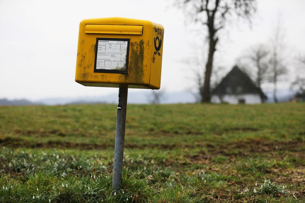 Ein Briefkasten der Deutschen Post steht auf einer Wiese am Rand einer Siedlung im Bergischen Land (NRW). - Foto: Oliver Berg/dpa