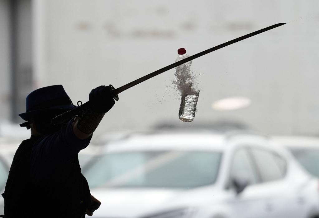 Joe Alexander zerteilt mit verbundenen Augen und einem Samurai-Schwert hochgeworfene Wasserflaschen, während des Weltrekordversuchs im Elbtor in der Hamburg Altona VW Niederlassung. Die Rekordversuche finden in Rahmen des siebzigsten Guinness World Records Day statt. - Foto: Marcus Brandt/dpa