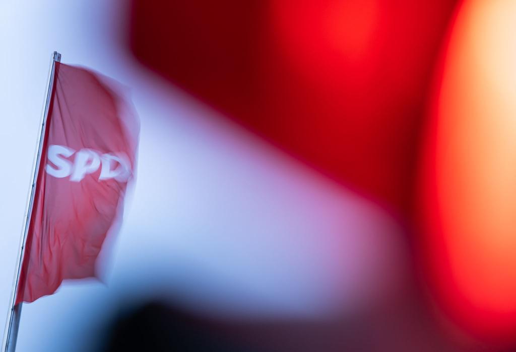 Eine SPD-Flagge weht hinter einer roten Ampel. Die Partei diskutiert über ihren Kanzlerkandidaten für die kommende Bundestagswahl. - Foto: Hannes P. Albert/dpa