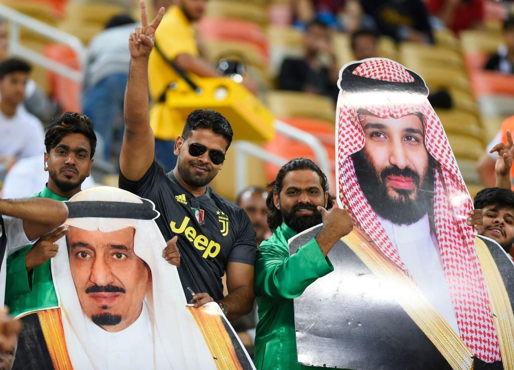 Saudische Fußballfans finden die Sport-Strategie des Königreichs um Kronprinz Mohammed bin Salman (auf dem rechten Plakat) gut. - Foto: ---/AP/dpa