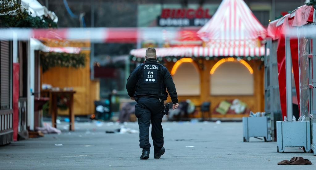 Ein Polizist geht hinter einer Absperrung am Magdeburger Weihnachtsmarkt. - Foto: Jan Woitas/dpa