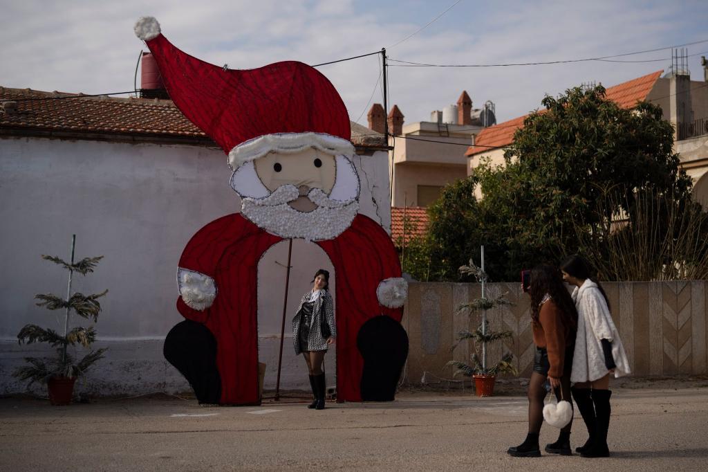 Eine junge Frau posiert für ein Foto an einer Weihnachtsdekoration auf einem Platz in einem christlichen Viertel in der syrischen Stadt Homs. - Foto: Leo Correa/AP/dpa