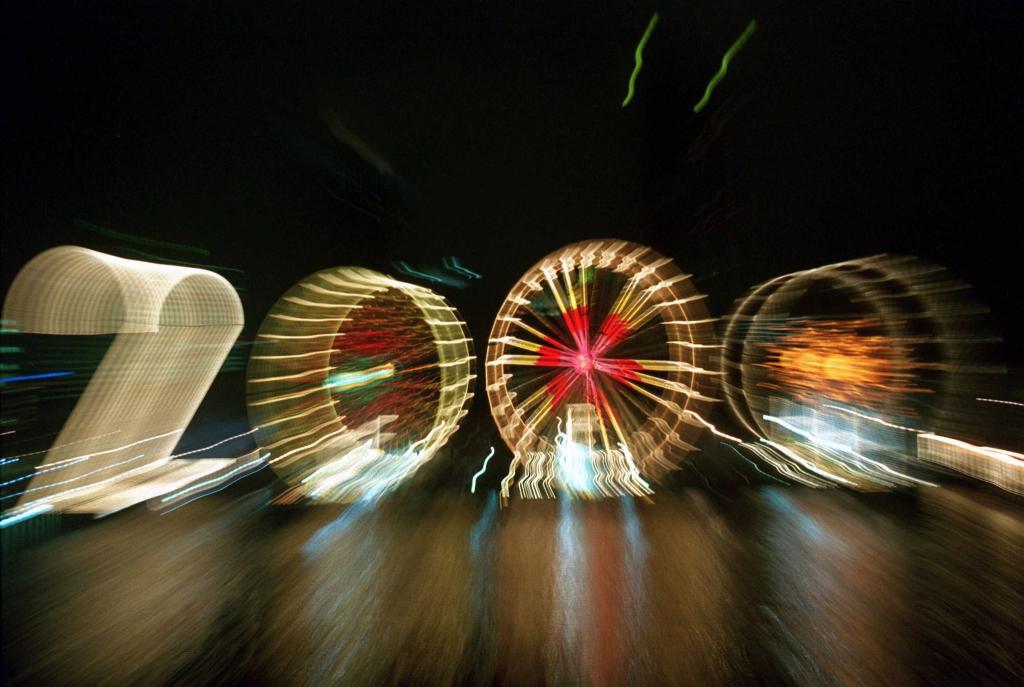 25 Jahre alt ist dieses «2000»-Foto: Ein Zoom-Effekt verfremdet eine große «2» und drei Riesenräder am Mainufer in Frankfurt in der Silvesternacht 1999/2000. - Foto: Arne Dedert/dpa