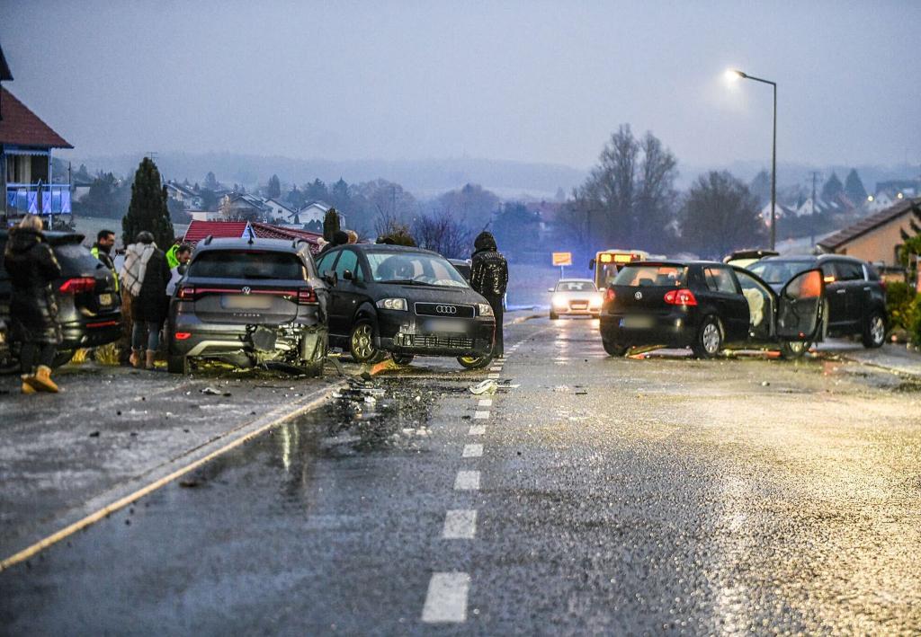 Nach einem Unfall bei Glatteis mit mehreren Fahrzeugen in Baden-Württemberg stehen Helfer und Beteiligte an den Autos auf einer Straße. - Foto: Jason Tschepljakow/dpa